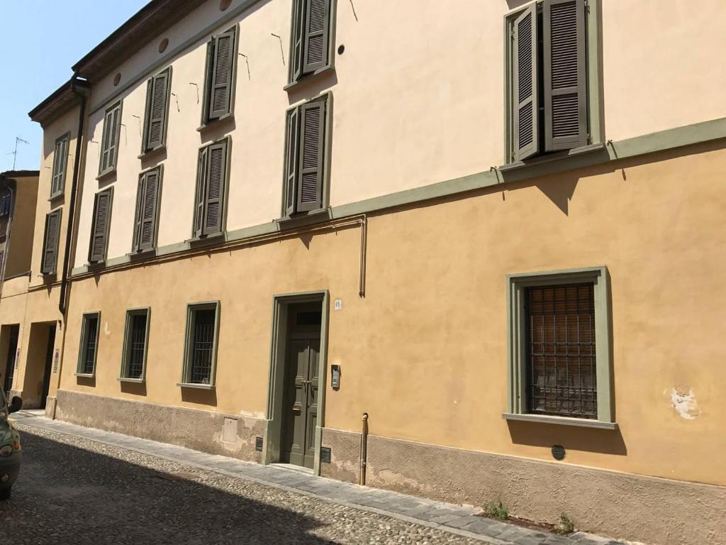 ein gelbes Gebäude mit einer Tür und Fenstern in der Unterkunft Amici Miei Rooms in Cremona