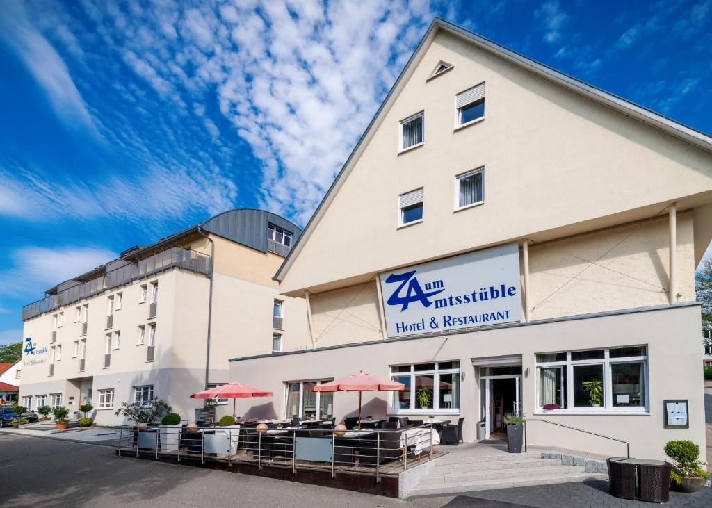 ein Hotel mit Tischen und Sonnenschirmen davor in der Unterkunft Amtsstüble Hotel & Restaurant in Mosbach