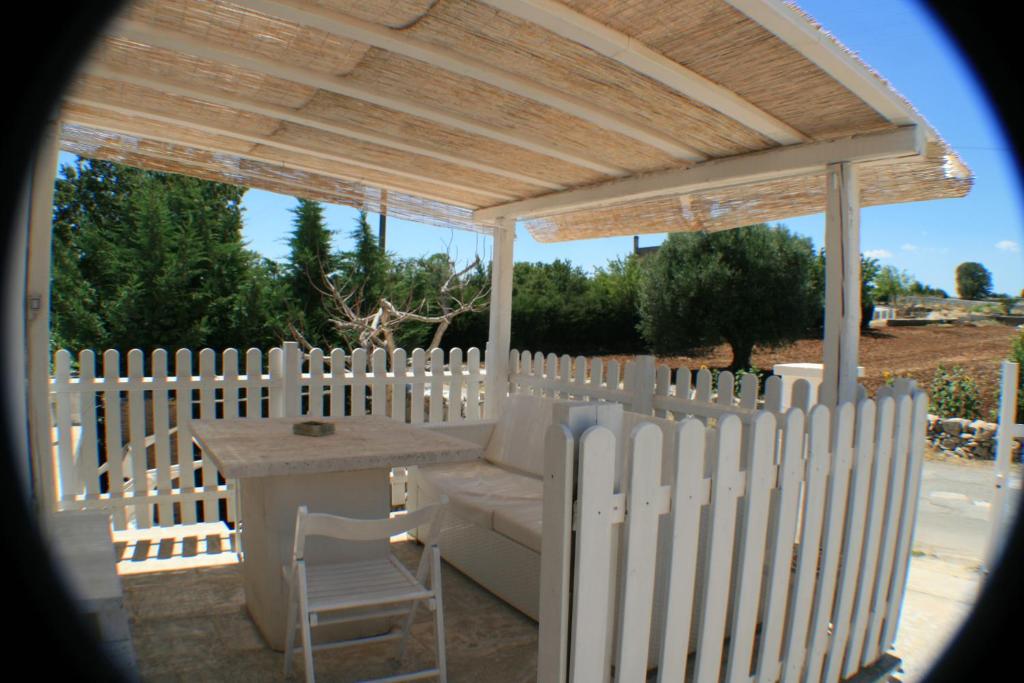 a white gazebo with a table and a white fence at Casolare Capitolo in Cisternino