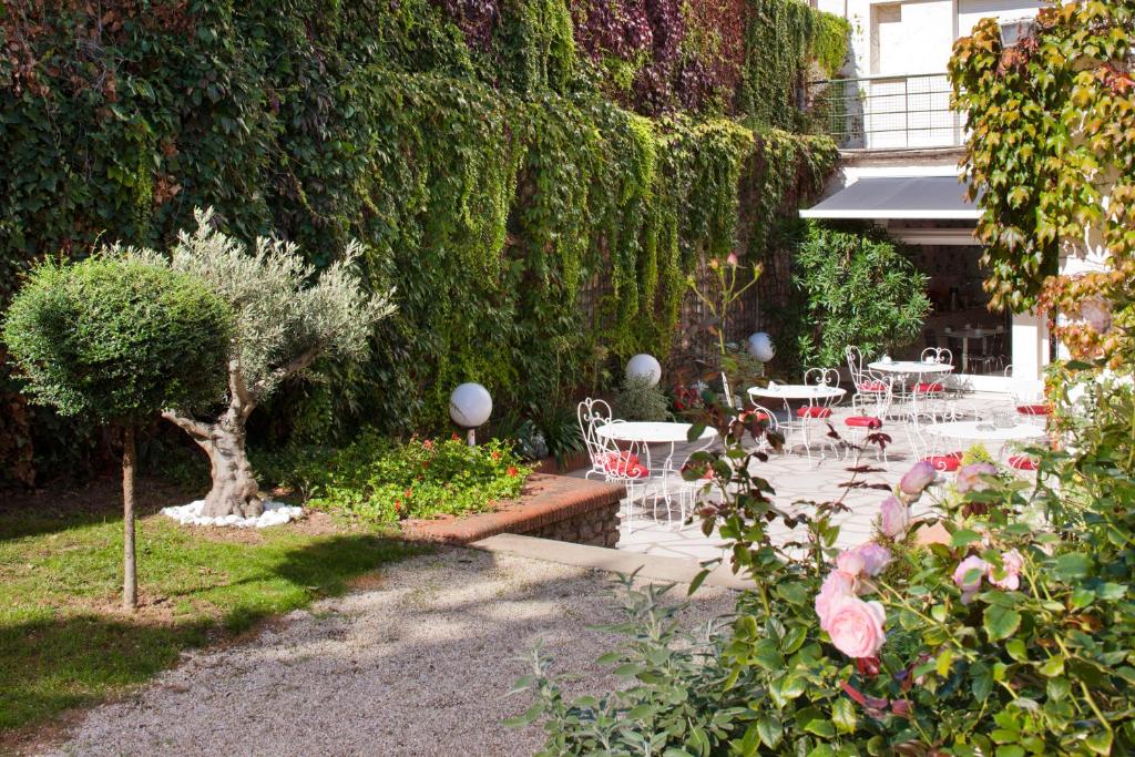 ニオールにあるGrand Hôtel Niort Centreのテーブルと椅子と生垣のある庭園