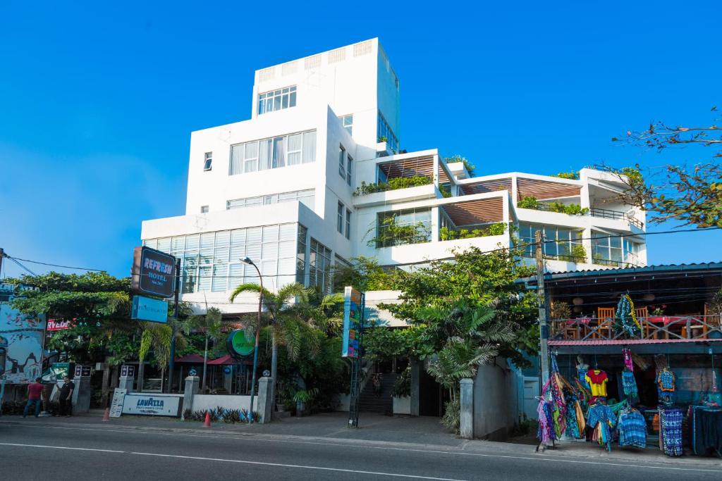 a tall white building on the side of a street at Refresh Hotel Hikkaduwa in Hikkaduwa