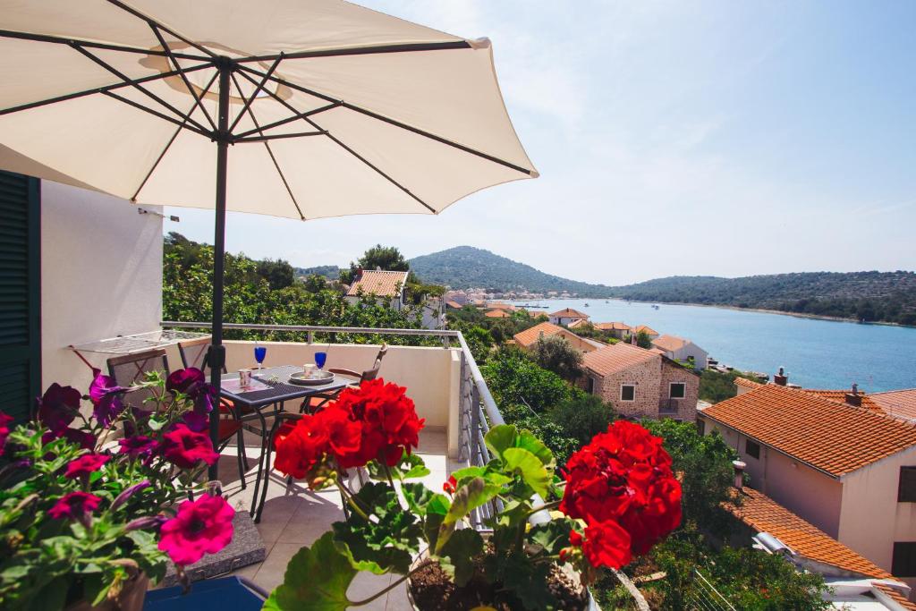 een balkon met een tafel, een parasol en bloemen bij Apartments Berovic Kaprije in Kaprije