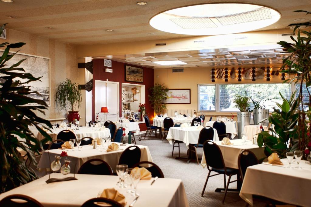 a dining room with white tables and chairs at Logis Arcombelle in Montigny-le-Roi