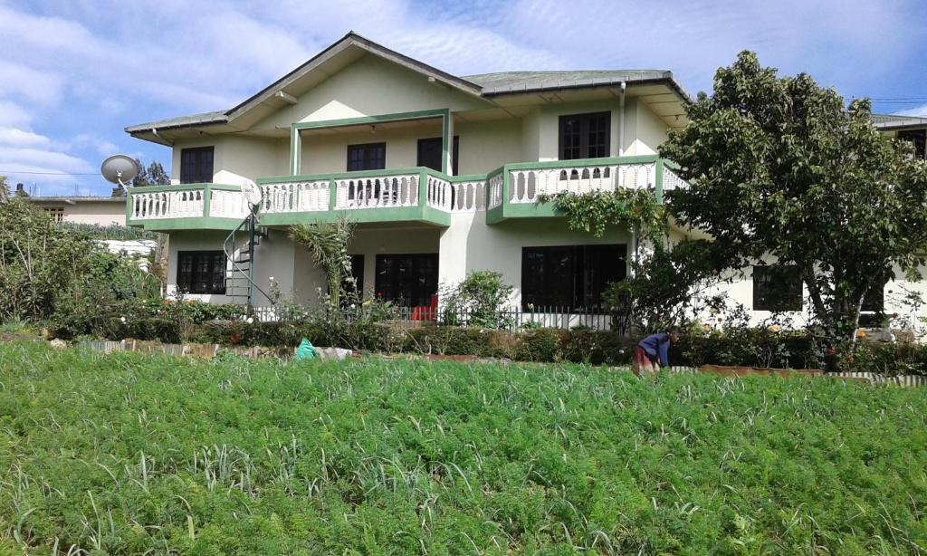 een wit huis met een balkon op een tuin bij Avon Field Holiday Bungalow in Nuwara Eliya
