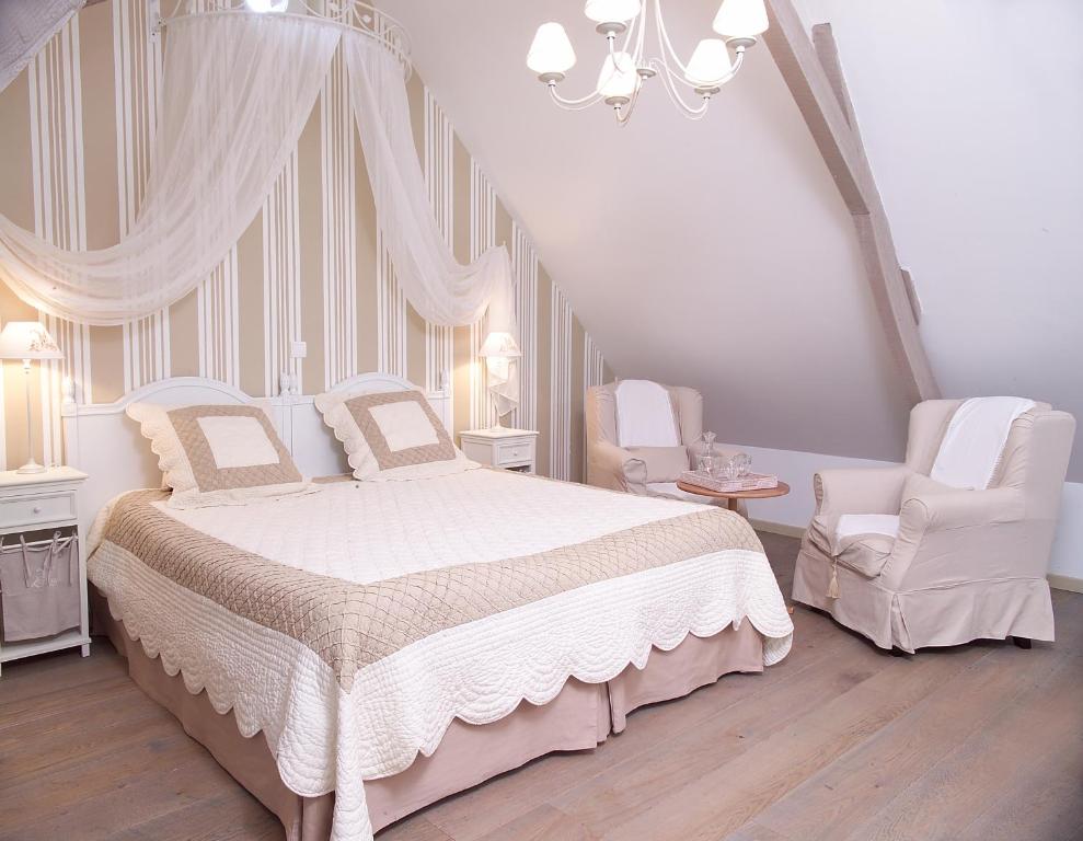 a white bedroom with a bed and two chairs at Côte d&#39;Opale - La Ferme des Saules in Millam