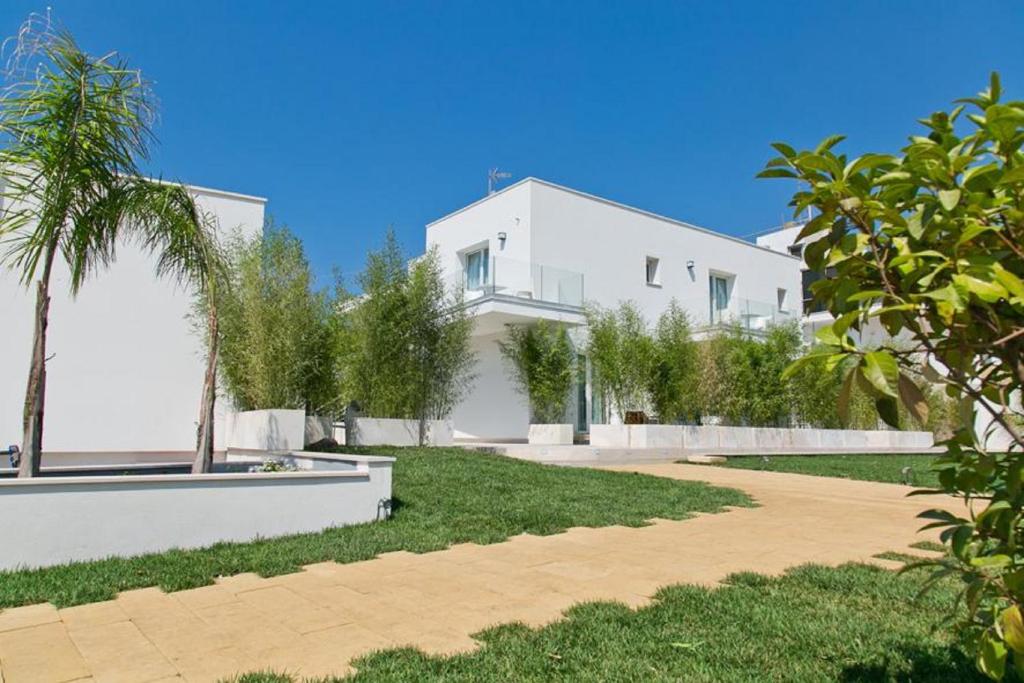 a white house with a palm tree in front of it at Terra d'Acqua Resort & SPA in Torre Mozza