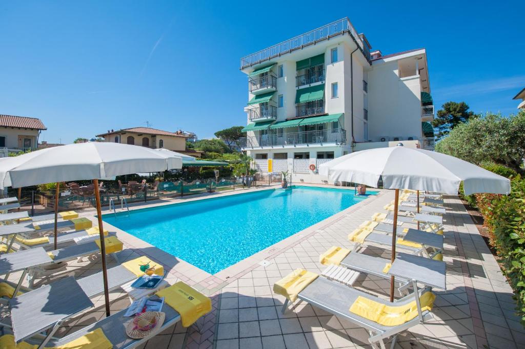 a swimming pool with chairs and umbrellas next to a building at Hotel Suisse in Marina di Pietrasanta