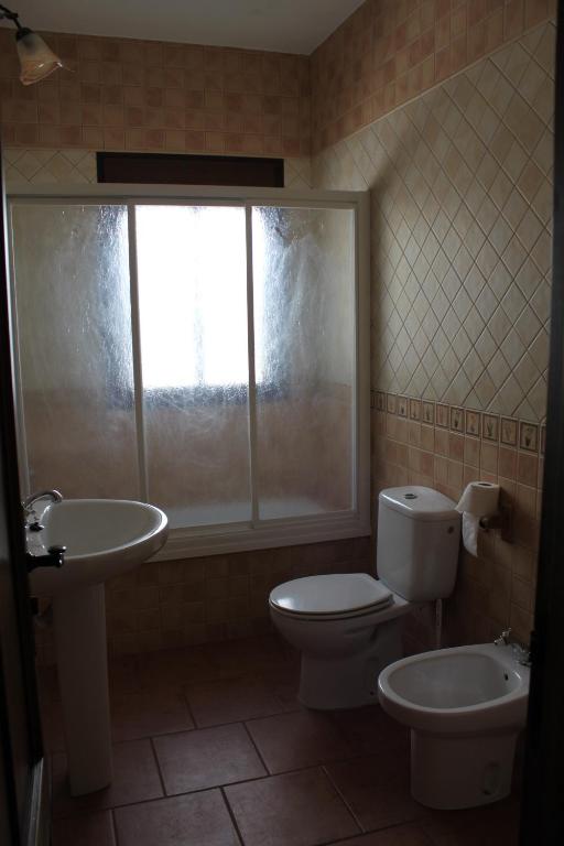 a bathroom with a toilet and a sink and a window at El Corral de Dolores in El Bosque