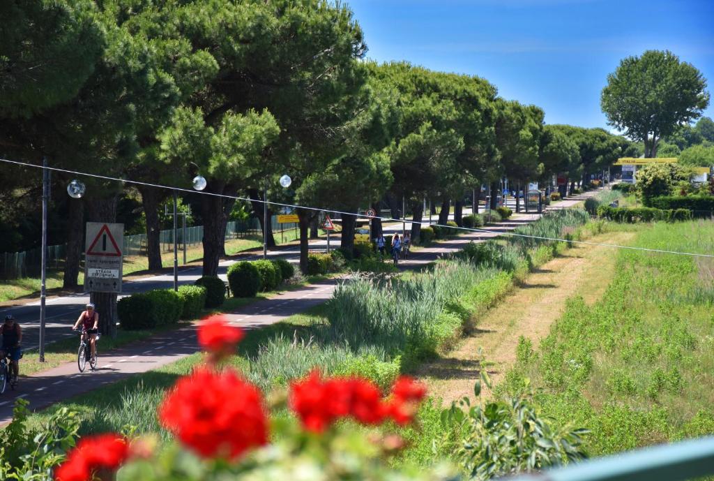 a person riding a bike down a street with red flowers at Hotel Ristorante Fortuna in Cavallino-Treporti
