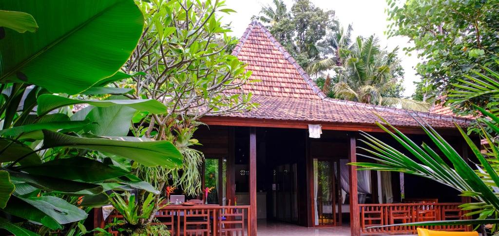 a building with a red roof with chairs and trees at Prama House in Ubud