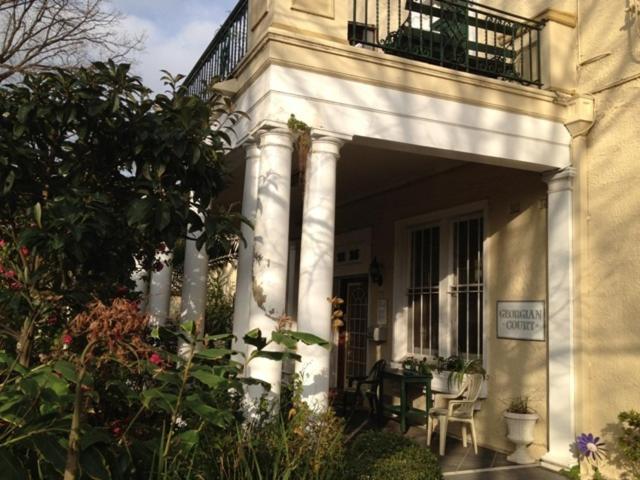 un edificio con balcón, mesa y sillas en Georgian Court B&B Guest House, en Melbourne