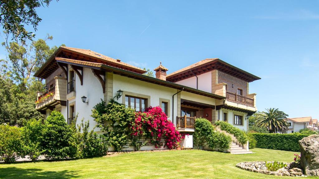 uma casa grande com um jardim verde em frente em Hotel Posada La Robleda em Arnuero