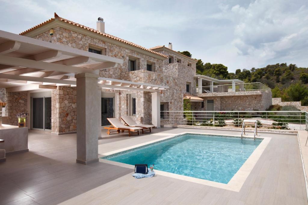 a villa with a swimming pool in front of a house at Edem Resort in Porto Heli