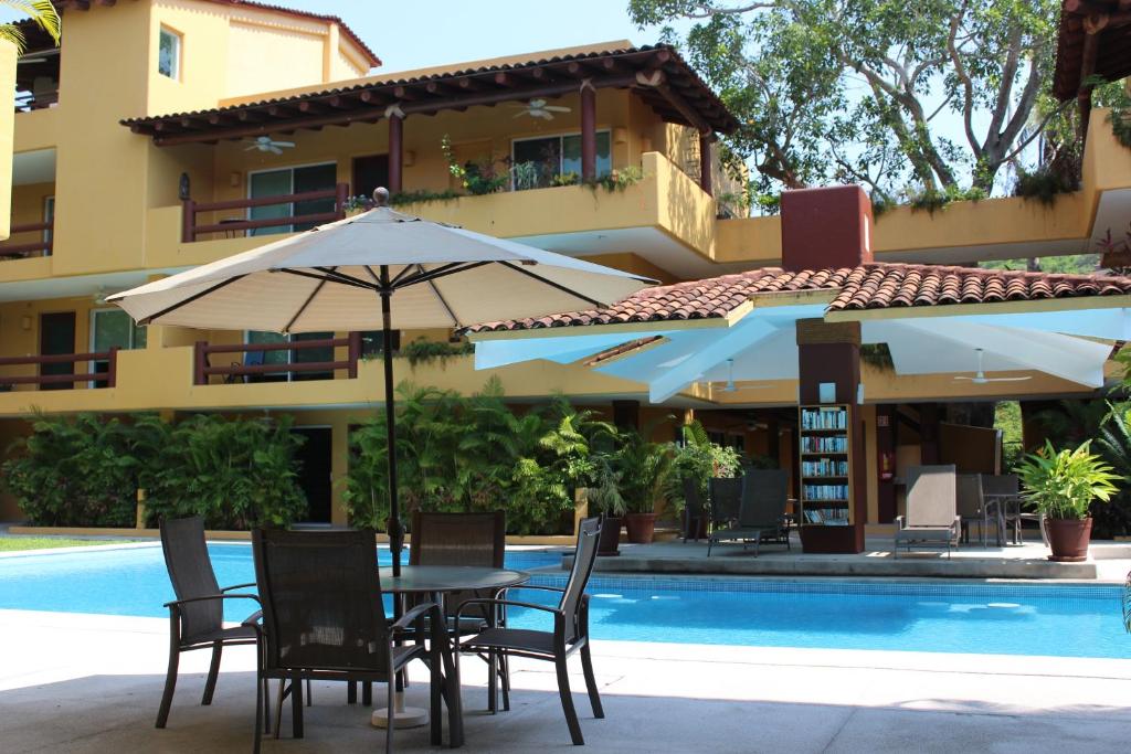 a table and chairs with an umbrella next to a pool at Los Mangos in Zihuatanejo