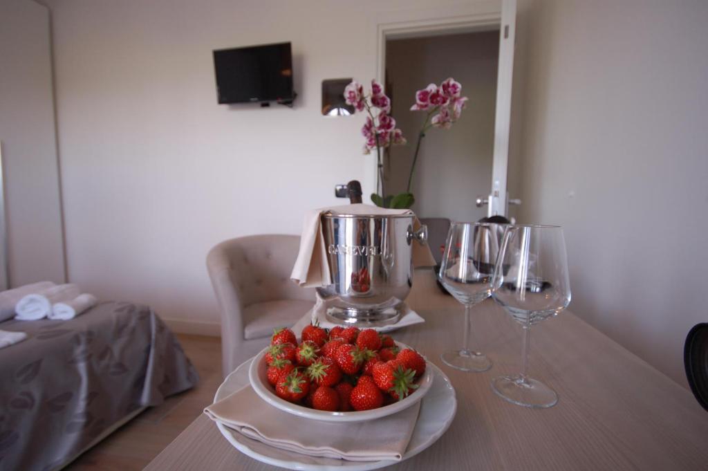 a table with a bowl of strawberries and wine glasses at Hotel Ristorante Fortuna in Cavallino-Treporti