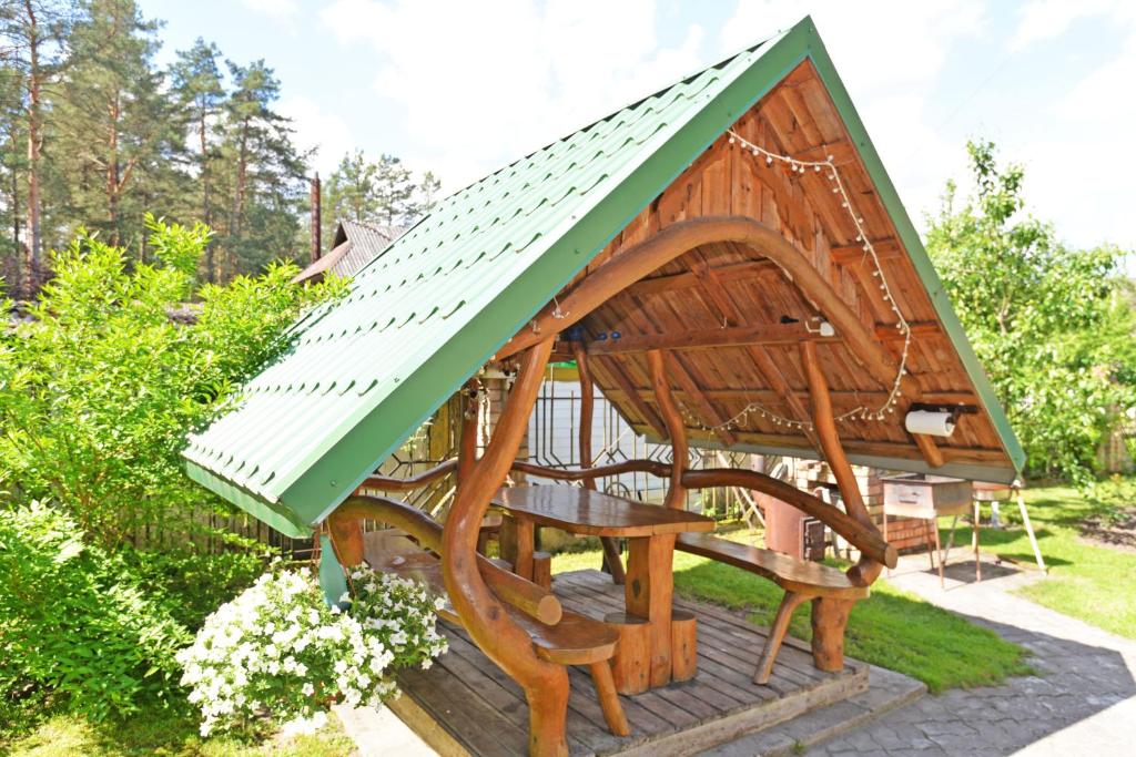 einen Pavillon mit einem Tisch und einem grünen Dach in der Unterkunft Apartamentai Šilas in Druskininkai