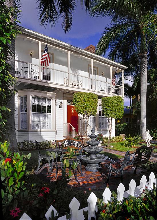 a white house with an american flag and a fountain at Sabal Palm House Bed and Breakfast in Lake Worth