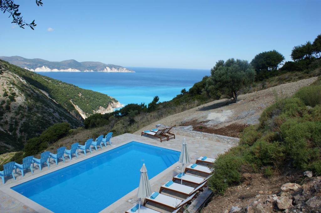 una piscina con sillas y el océano en el fondo en Myrtos View Apartments, en Anomeriá