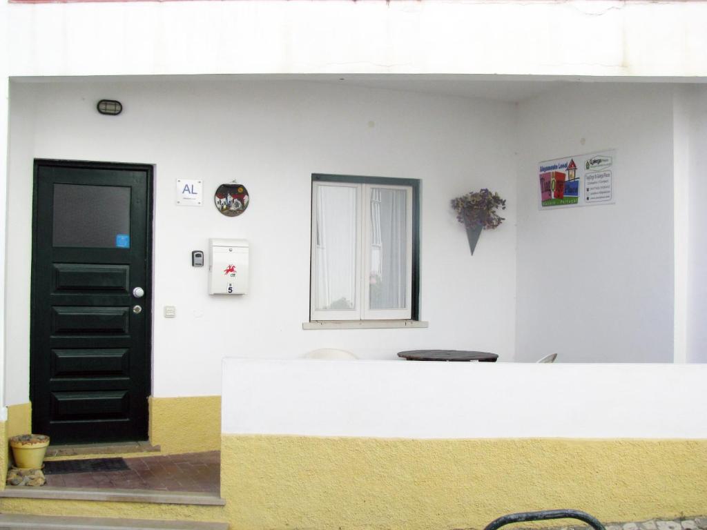 una pared blanca con una puerta negra y una ventana en Tiago & Jorge Guesthouse, en Nazaré