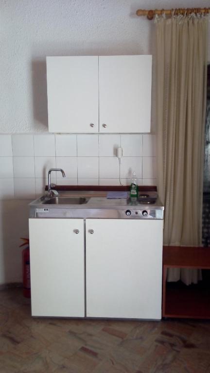 kuchnia z białymi szafkami i zlewem w obiekcie Akis Apartments Kontogialos-Pelekas w mieście Pelekas