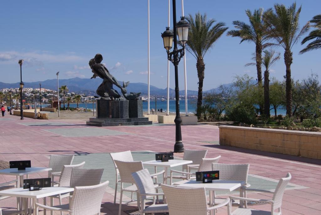 a group of tables and chairs with a statue at Hotel Doña Luisa in San Luis de Sabinillas