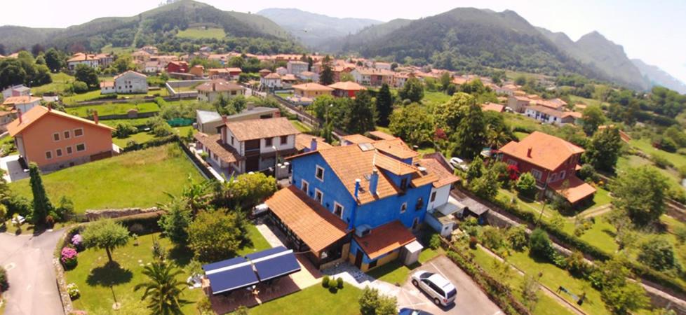 ein großes blaues Haus in einer kleinen Stadt mit Bergen in der Unterkunft Hotel La Casona de Nueva in Nueva de Llanes