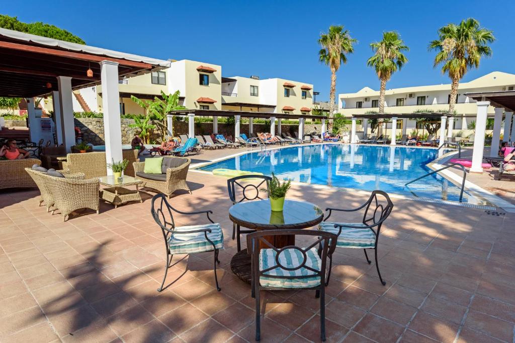 a patio with a table and chairs next to a pool at Pefkos Village Resort in Pefki Rhodes