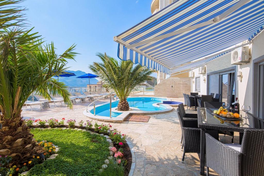a patio with a table and chairs and a swimming pool at Montelux Apartments in Budva