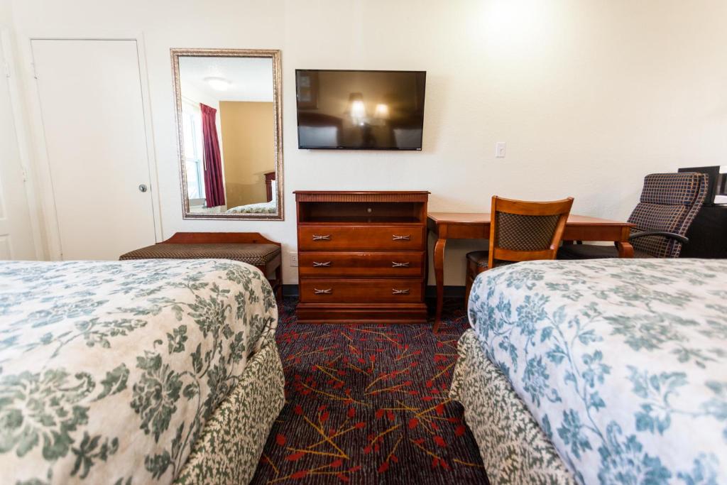 a room with two beds and a desk and a mirror at Lockhart Inn in Lockhart