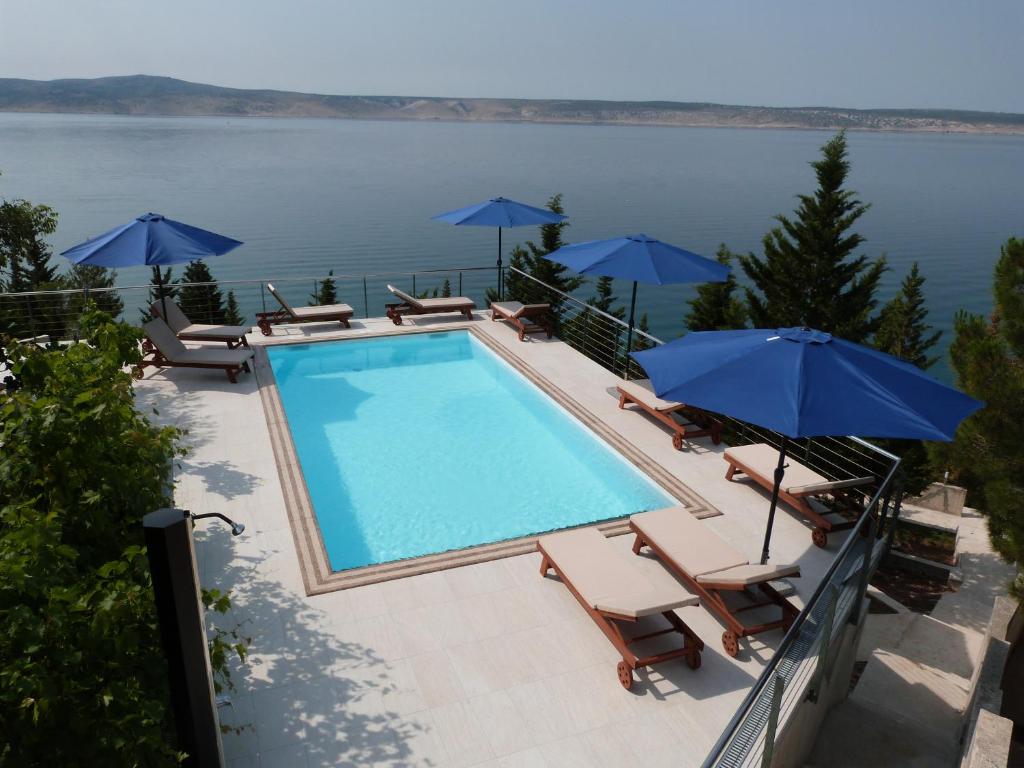 einen Pool mit Stühlen und Sonnenschirmen in der Unterkunft Maria Apartments in Starigrad-Paklenica