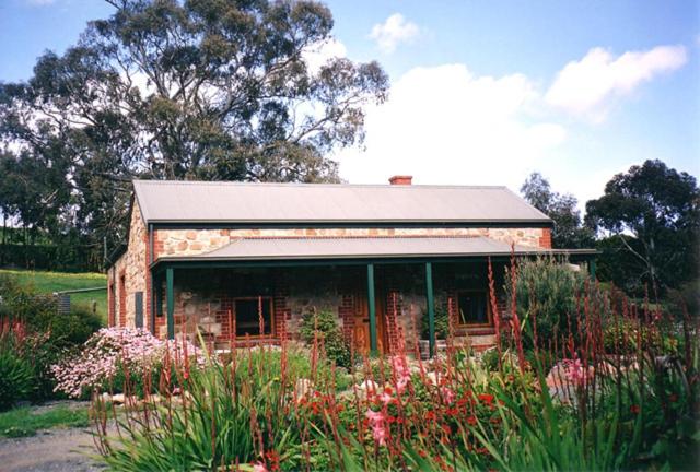 ein kleines Backsteinhaus mit Blumen davor in der Unterkunft Amanda's Cottage 1899 in McLaren Vale