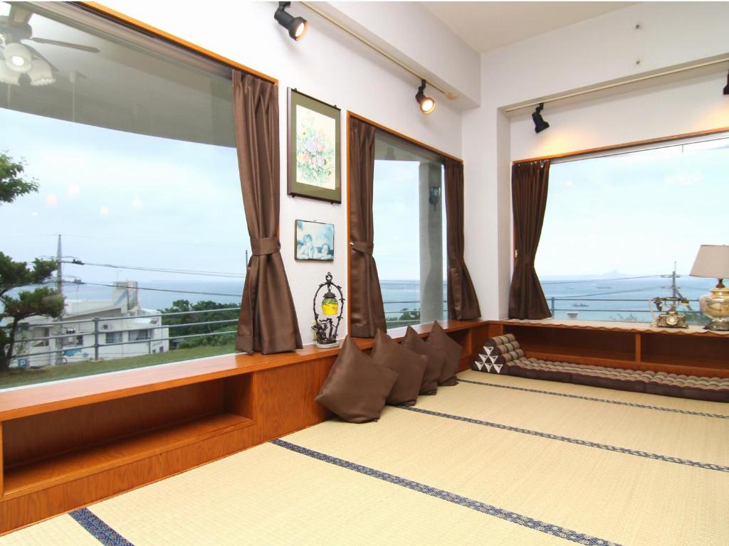 Cette chambre dispose de grandes fenêtres offrant une vue sur l'océan. dans l'établissement Minshuku Tantawan -SEVEN Hotels and Resorts-, à Motobu