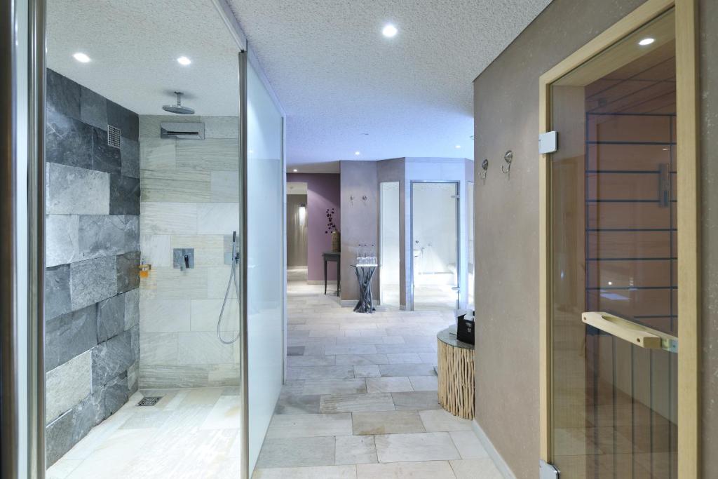 a bathroom with a walk in shower and a glass door at Hotel Strand am Königshafen in List