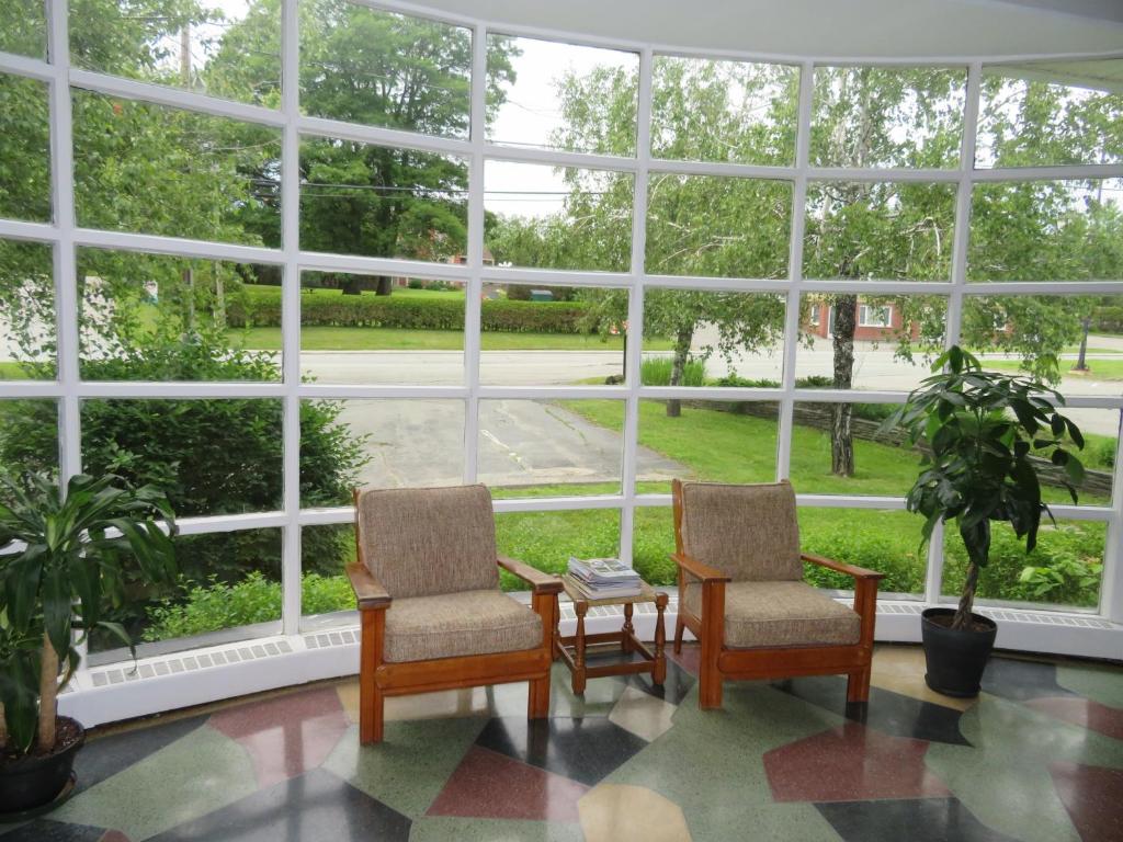 2 sillas y una mesa frente a una gran ventana en La Paysanne Motel & Hotel, en Sherbrooke