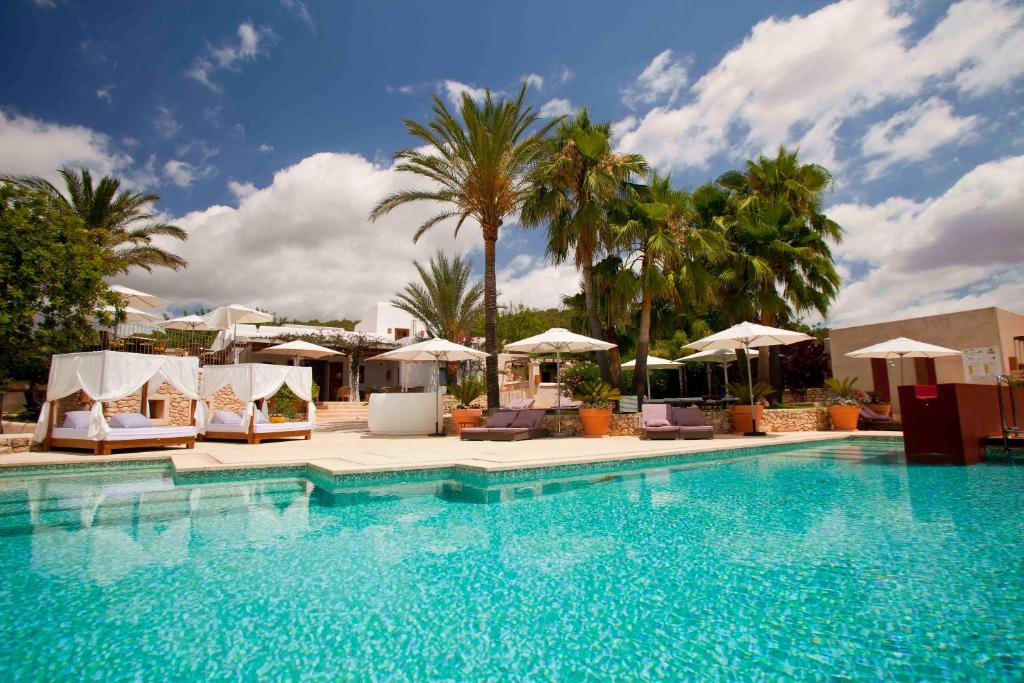 une grande piscine avec des chaises et des parasols dans l'établissement Can Lluc Hotel Rural, à Sant Rafael de Sa Creu