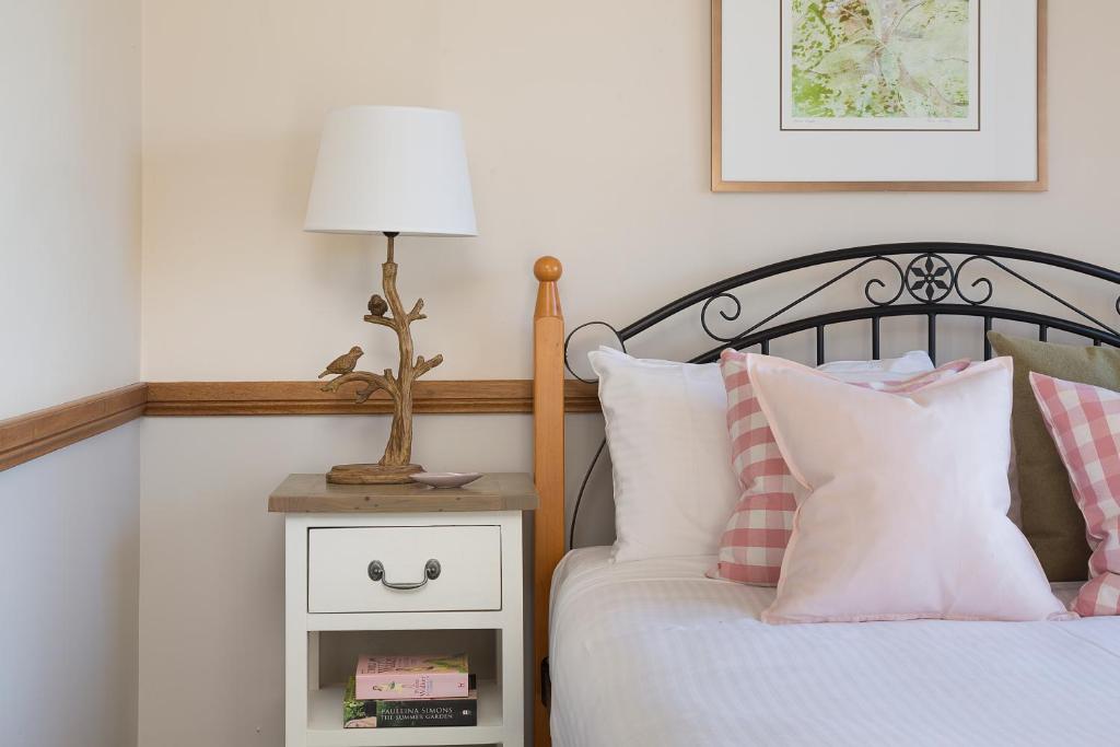 a bedroom with a bed and a lamp on a night stand at Windsors Edge Cottage Pokolbin in Rothbury