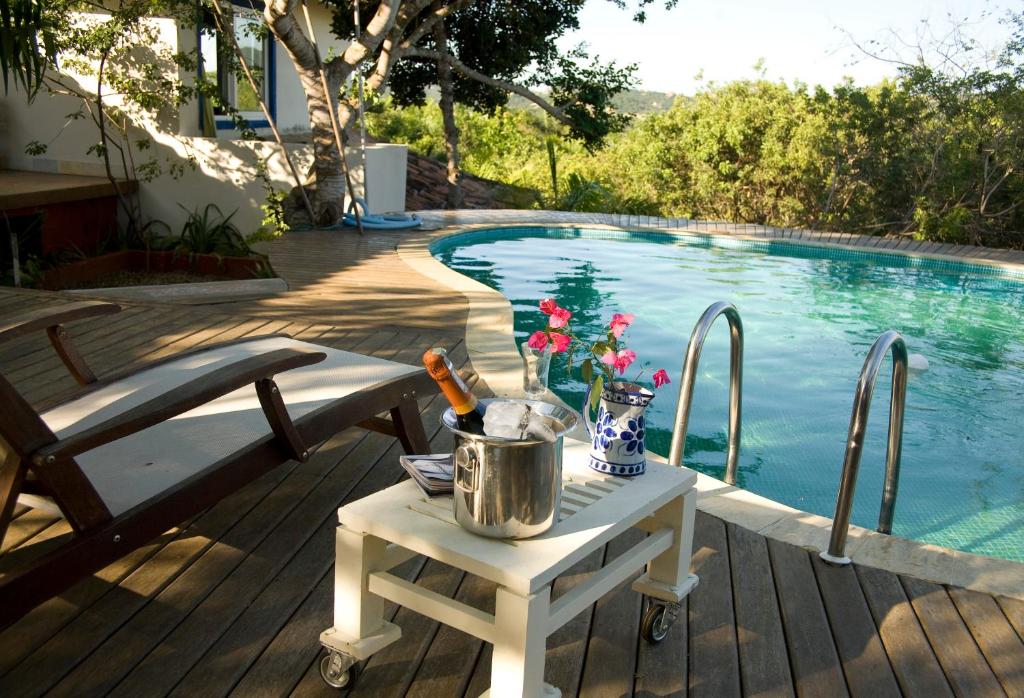 una mesa blanca junto a una piscina con una mesa en Ferradura Parque Pousada, en Búzios