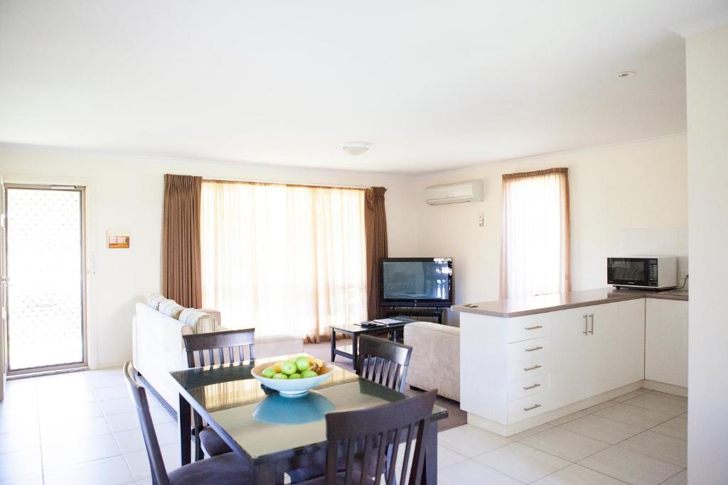 a kitchen with a table and chairs and a refrigerator at Echuca Moama Holiday Villas in Moama
