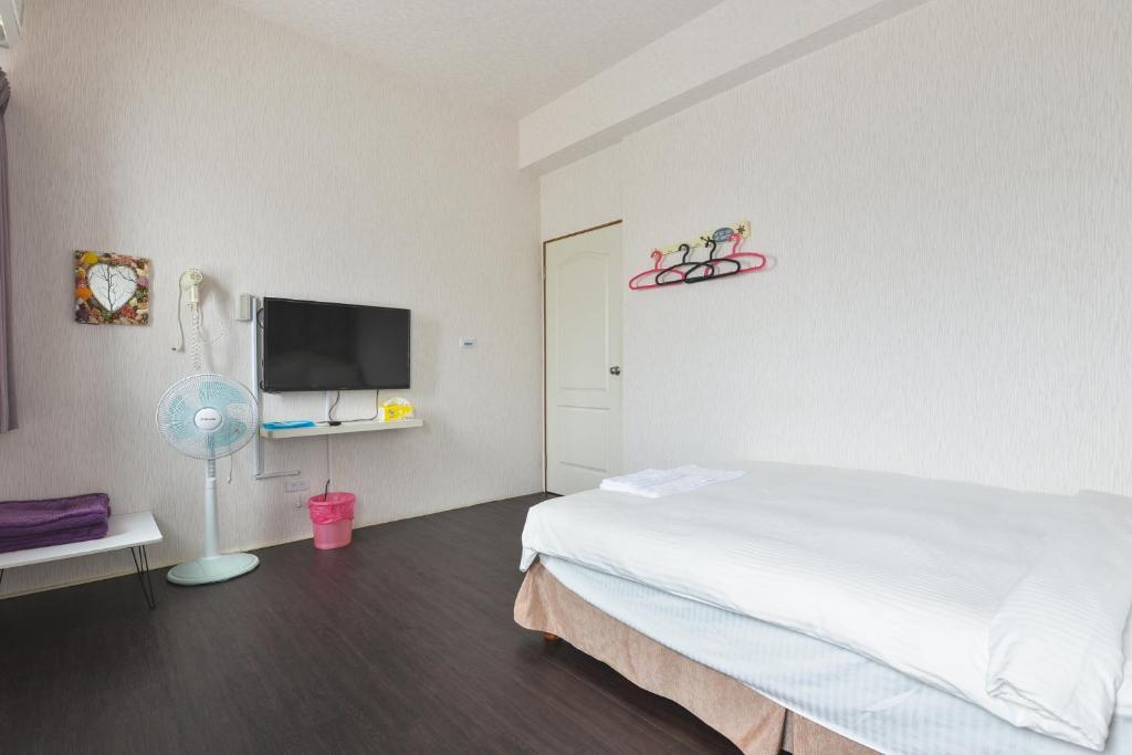 a bedroom with a bed and a flat screen tv at Light Blue Hostel in Hengchun South Gate