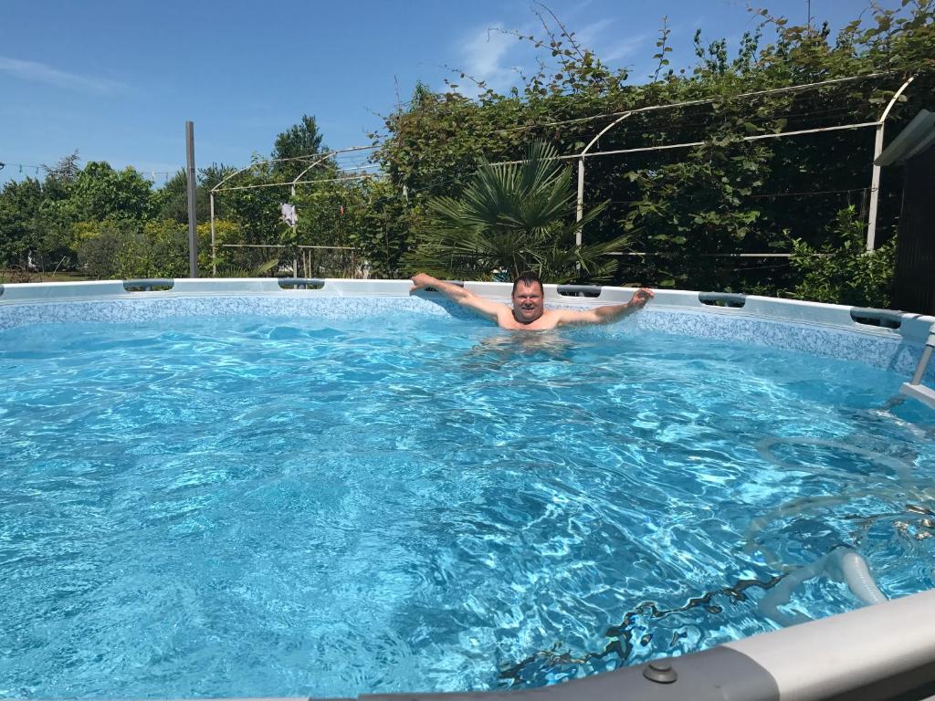un hombre está en una piscina en Vse Dlya Vas Guest House, en Gudauta