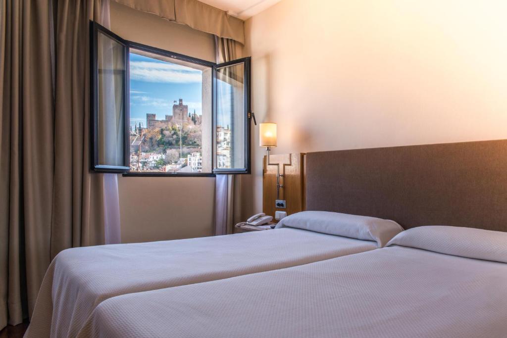 Habitación de hotel con 2 camas y ventana en Hotel Inglaterra, en Granada