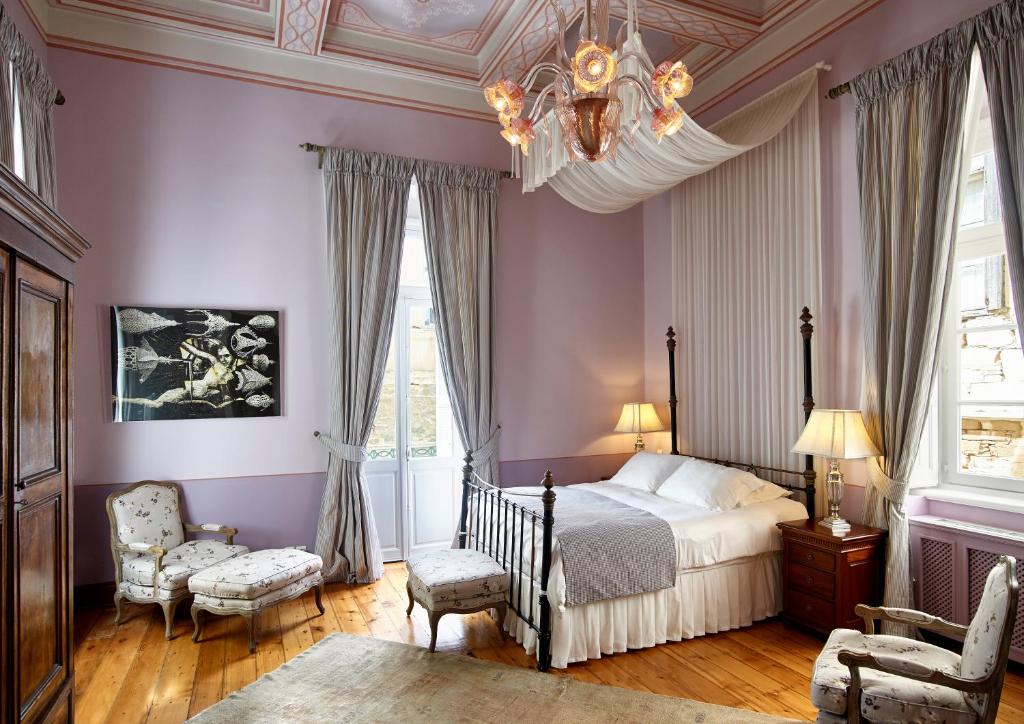 a bedroom with purple walls and a bed and a chandelier at Hotel Ploes in Ermoupoli