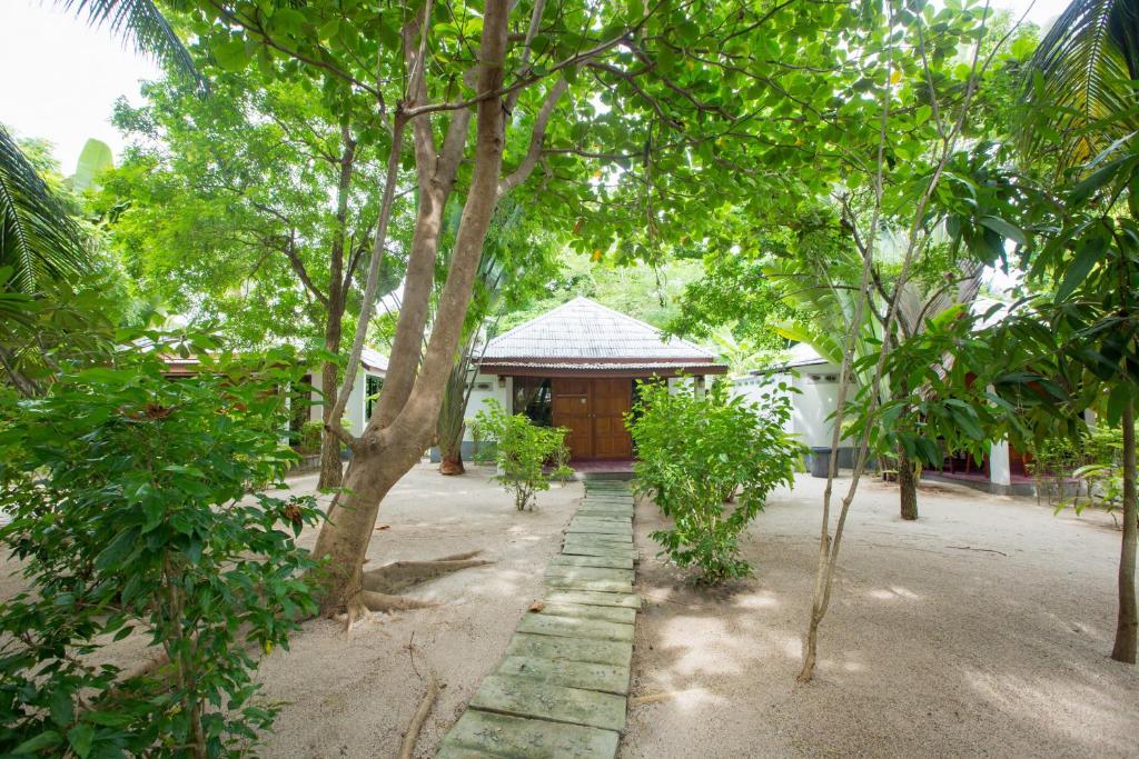a building in the middle of a garden with trees at Da Kanda Villa Beach Resort in Thong Sala