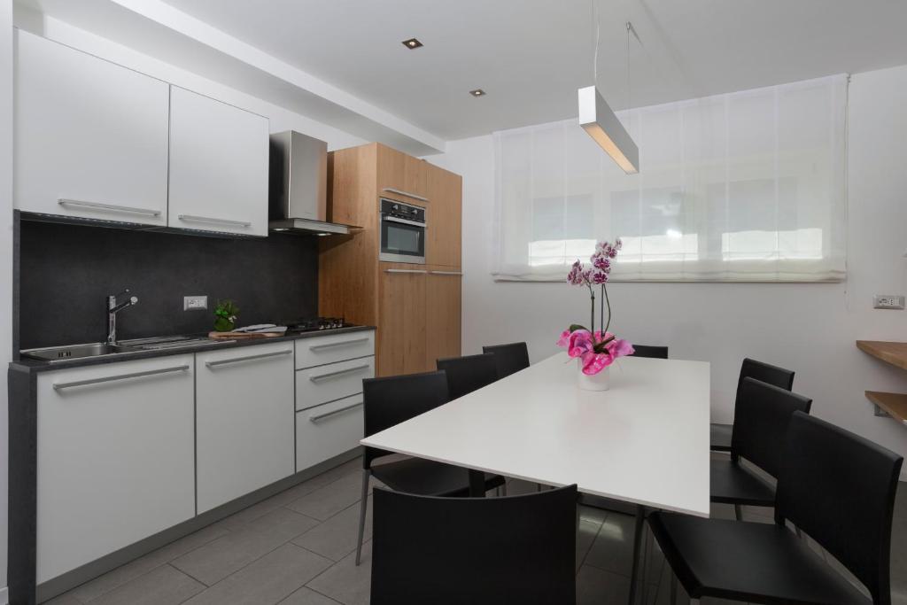 una cucina con armadi bianchi e tavolo e sedie bianchi di Appartamento Mirabell ad Andalo