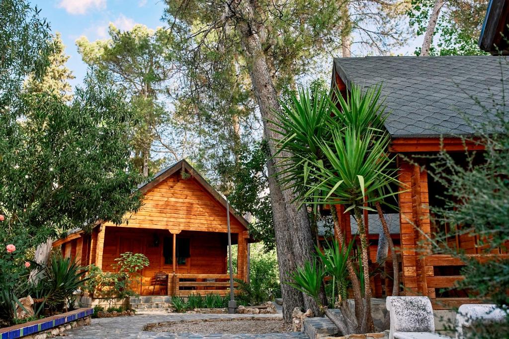 una cabaña de madera con un árbol delante en Balneario San Andres, en Canena