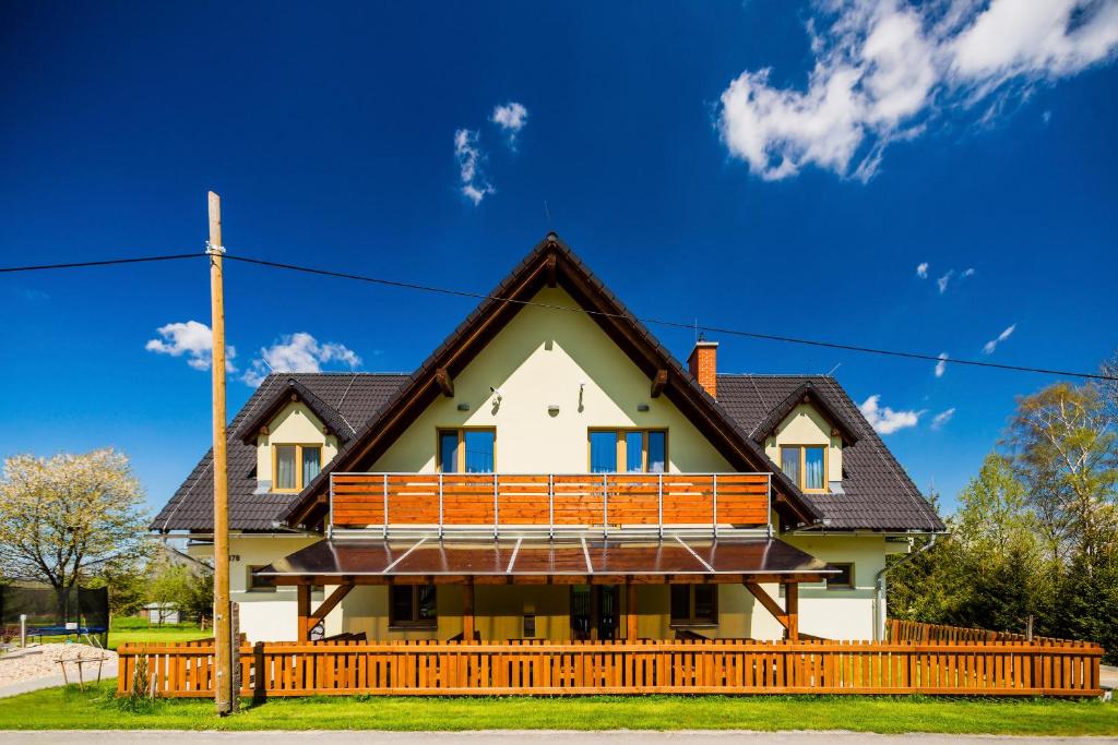 a house with a wooden fence in front of it at Penzion U Barana in Trojanovice