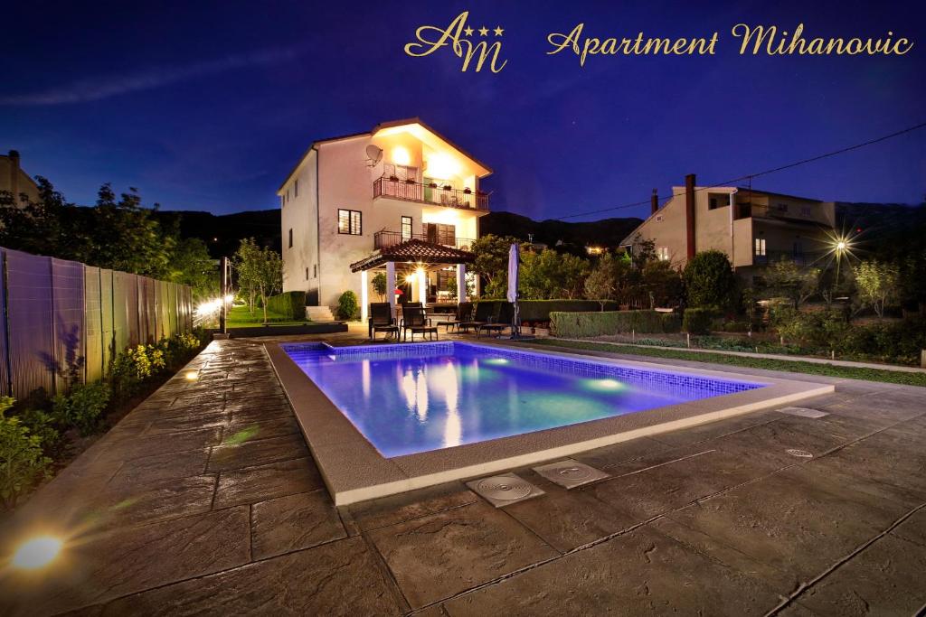 - une piscine en face d'une maison la nuit dans l'établissement Apartment Mihanovic, à Žrnovnica