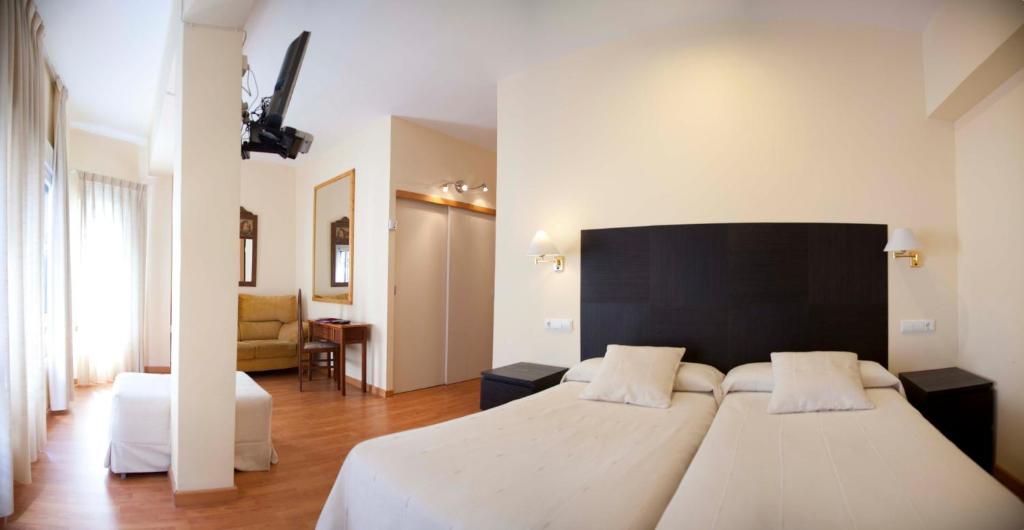 a bedroom with two white beds and a black headboard at Hostal Ruiz in Soria