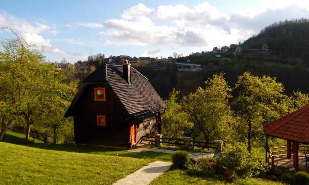 een klein huis op een grasheuvel met een hek bij Vacation Home Nana in Mokra Gora