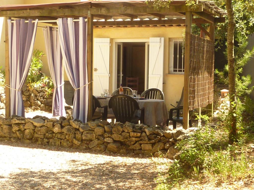 a patio with a table and a stone wall at Gîte de Saint Cassien in Montauroux